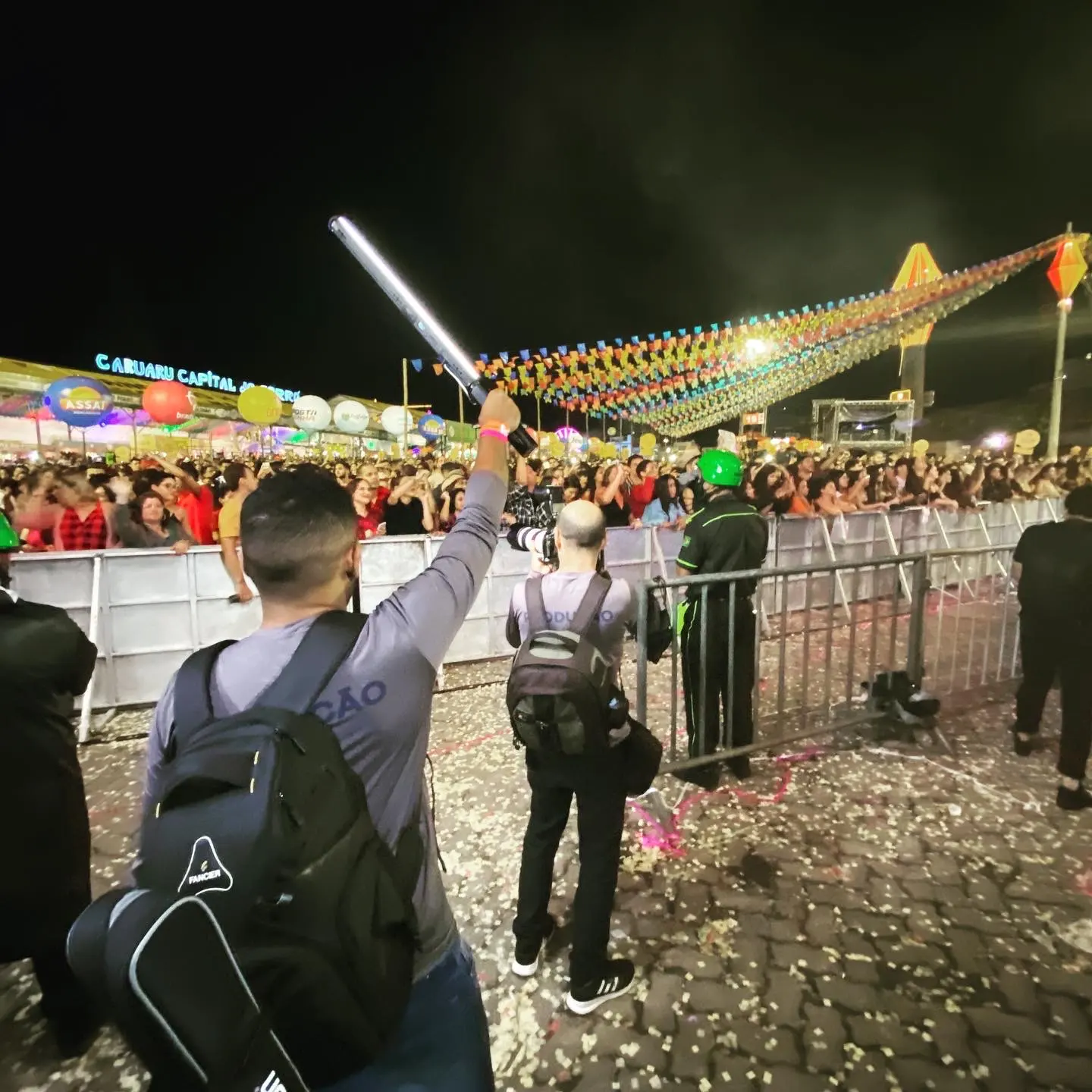Equipe da Cacoete com bastão de luz e câmera na frente do palco do São João de Caruaru