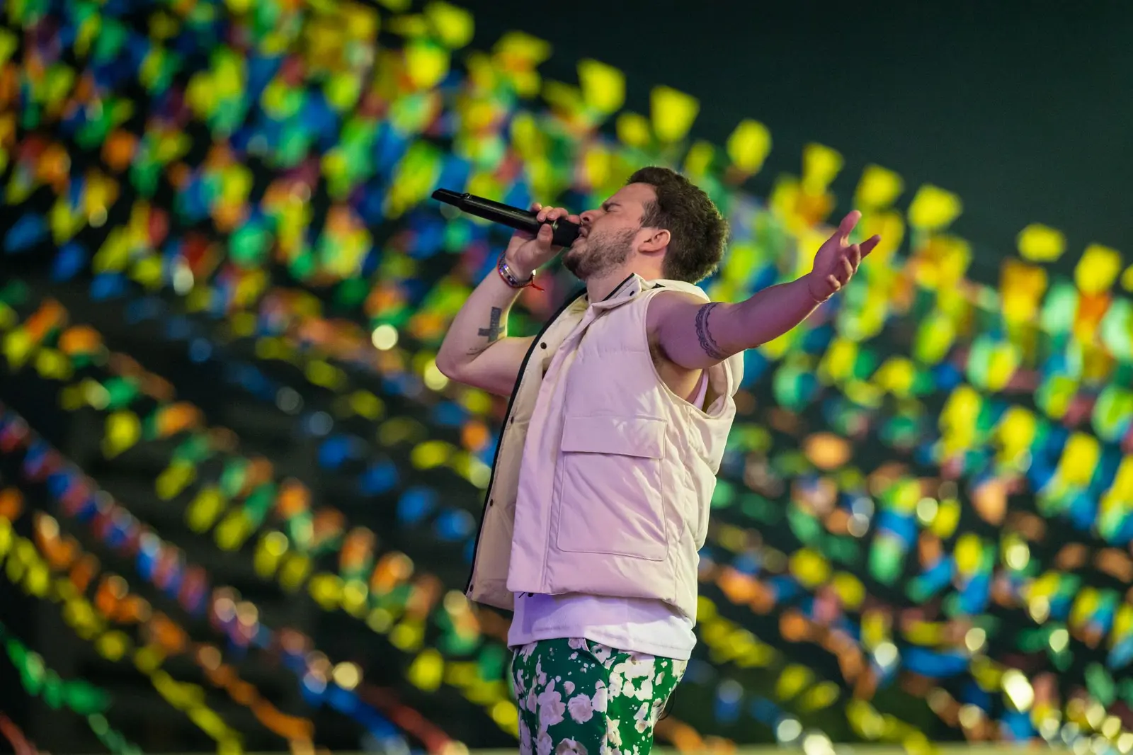 Cantor no palco do São João de Caruaru com bandeirolas coloridas ao fundo